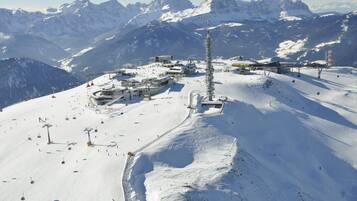 Un centro de esquí cubierto de nieve con telesillas, una torre alta y vistas a la montaña.