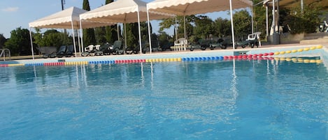 Una piscina al aire libre de temporada, sombrillas