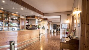 Un hall de hotel con mostrador de recepción, una zona de bar con diferentes botellas y suelo de madera.