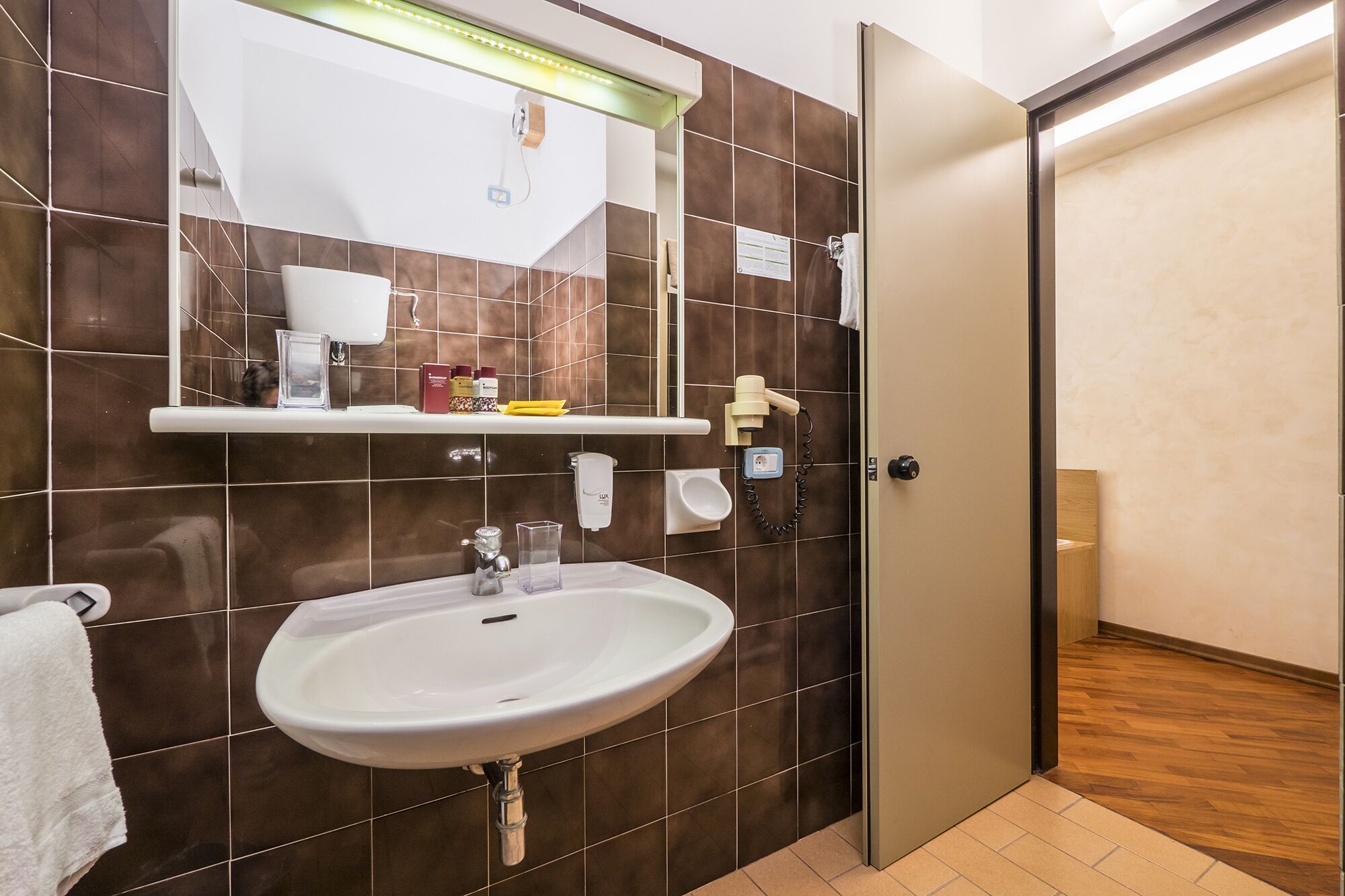 A bathroom with a white sink, a mirror, and a shower area.