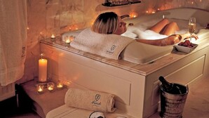 Un baño de spa con velas, una toalla y una copa de vino.