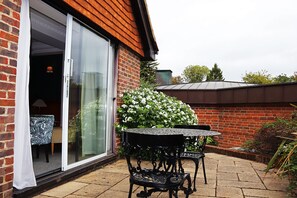 A patio with a table and chairs, a sliding glass door, and a brick wall. - Fredrick's Hotel Restaurant & Spa (Maidenhead)