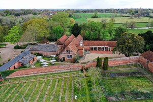 A large estate with multiple buildings, including a main house with a large garden and vineyard.