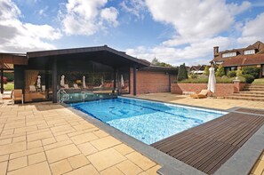 A swimming pool with a covered area, outdoor seating, and a brick house in the background. - Fredrick's Hotel Restaurant & Spa (Maidenhead)
