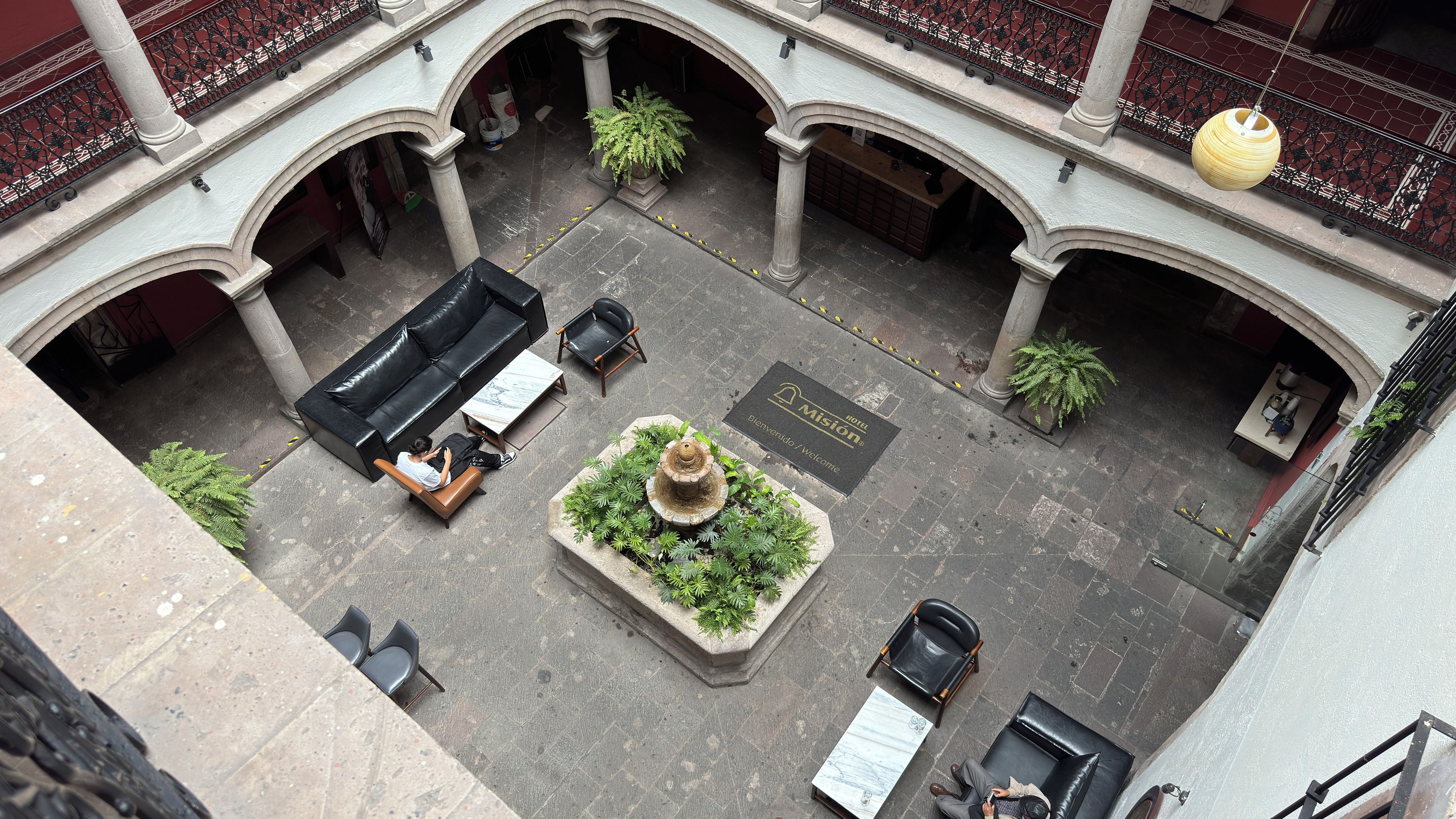 A courtyard with a fountain, seating areas, and a reception desk.