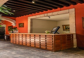 A reception desk with a tiled floor, framed artwork on the wall, and a potted plant.