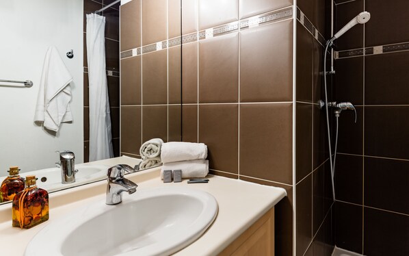 Un baño con lavamanos, espejo, toallero y ducha.