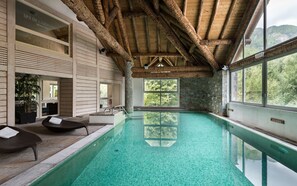 Un spa con interior de madera, piscina y vistas al bosque.