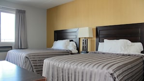 A hotel room with two beds, a nightstand with a lamp, and a window with curtains. - Victoria Motor Inn (Niagara Falls)