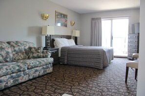A hotel room with a bed, a sofa, a dresser, and a chair. - Victoria Motor Inn (Niagara Falls)