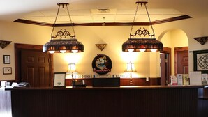 A reception desk with two hanging lamps, a framed certificate, a phone, and a sign for St. Brendan's Inn. - St. Brendan's Inn (Green Bay)