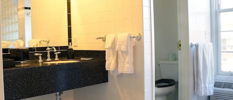A bathroom with a black countertop sink, white tiled walls, and a black and white checkered floor.