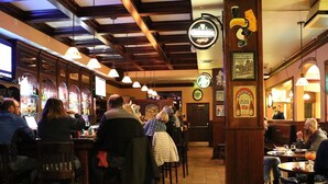 A bar with wooden beams, hanging lights, and patrons seated at tables. - St. Brendan's Inn (Green Bay)
