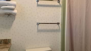 Un baño con inodoro, perchero para toallas y cortina de ducha.