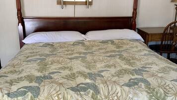 A bed with a floral bedspread, two wall-mounted lamps, and a wooden nightstand with a lamp.