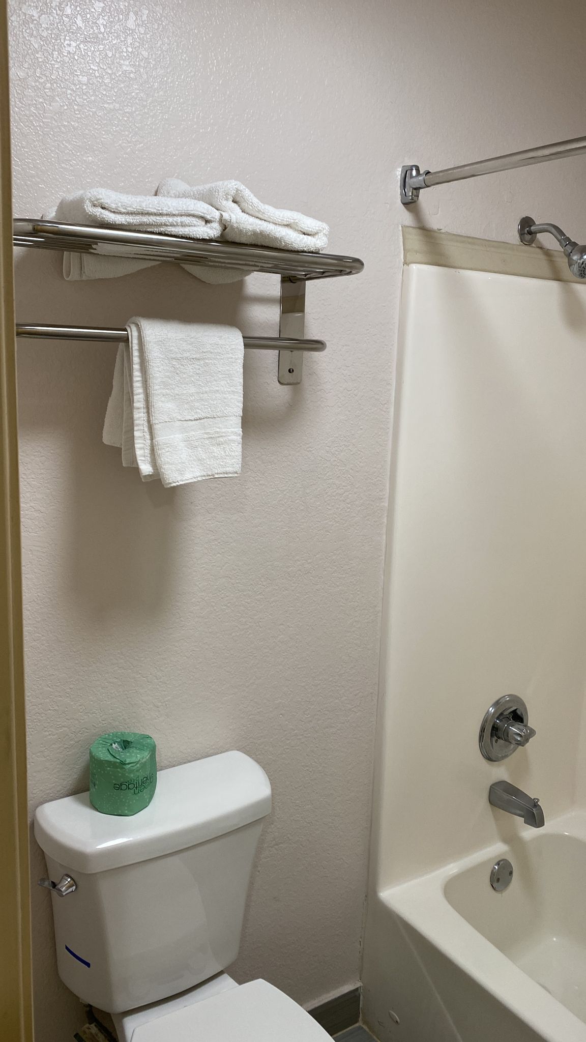 Une salle de bain équipée de toilettes, d’une douche et d’un porte-serviettes avec des serviettes pliées.