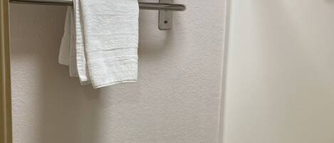Une salle de bain équipée de toilettes, d’une douche et d’un porte-serviettes avec des serviettes pliées.