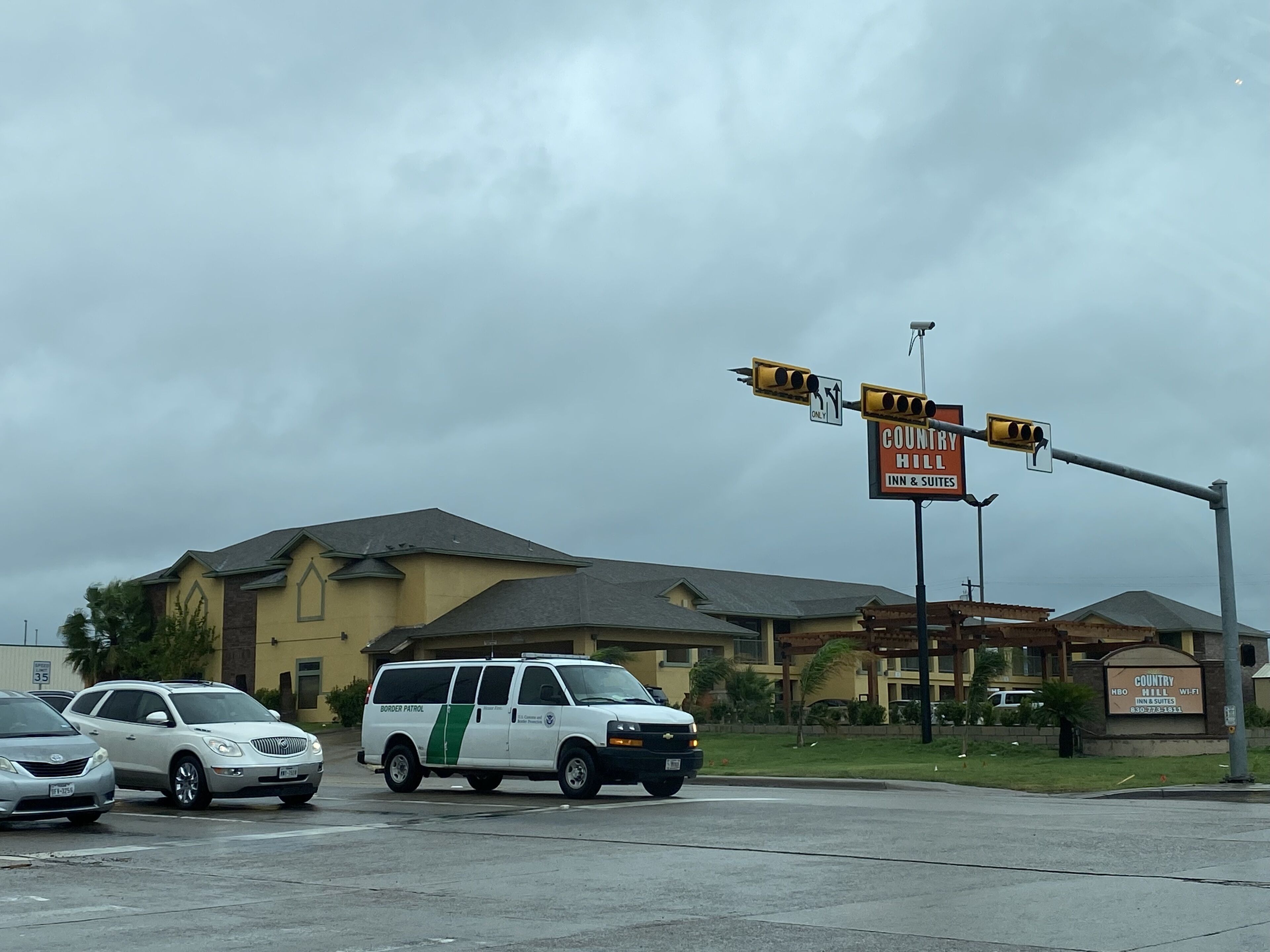 Un vehículo de patrulla fronteriza en una intersección con un cartel de Country Hill Inn & Suites al fondo.