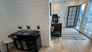 A modern room with a black desk, a chair, a small table with a plant, and a large window with a view.