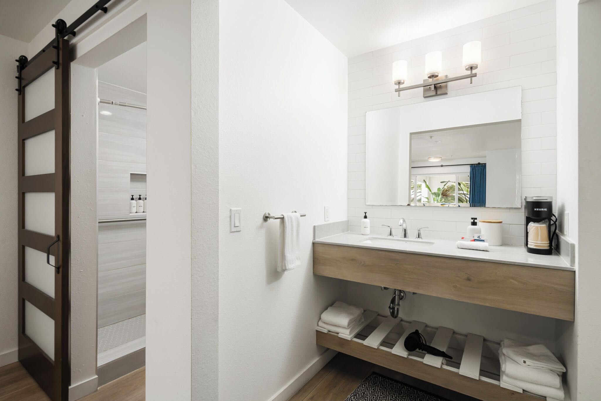 A modern bathroom with a wooden vanity, a large mirror, and a coffee machine.
