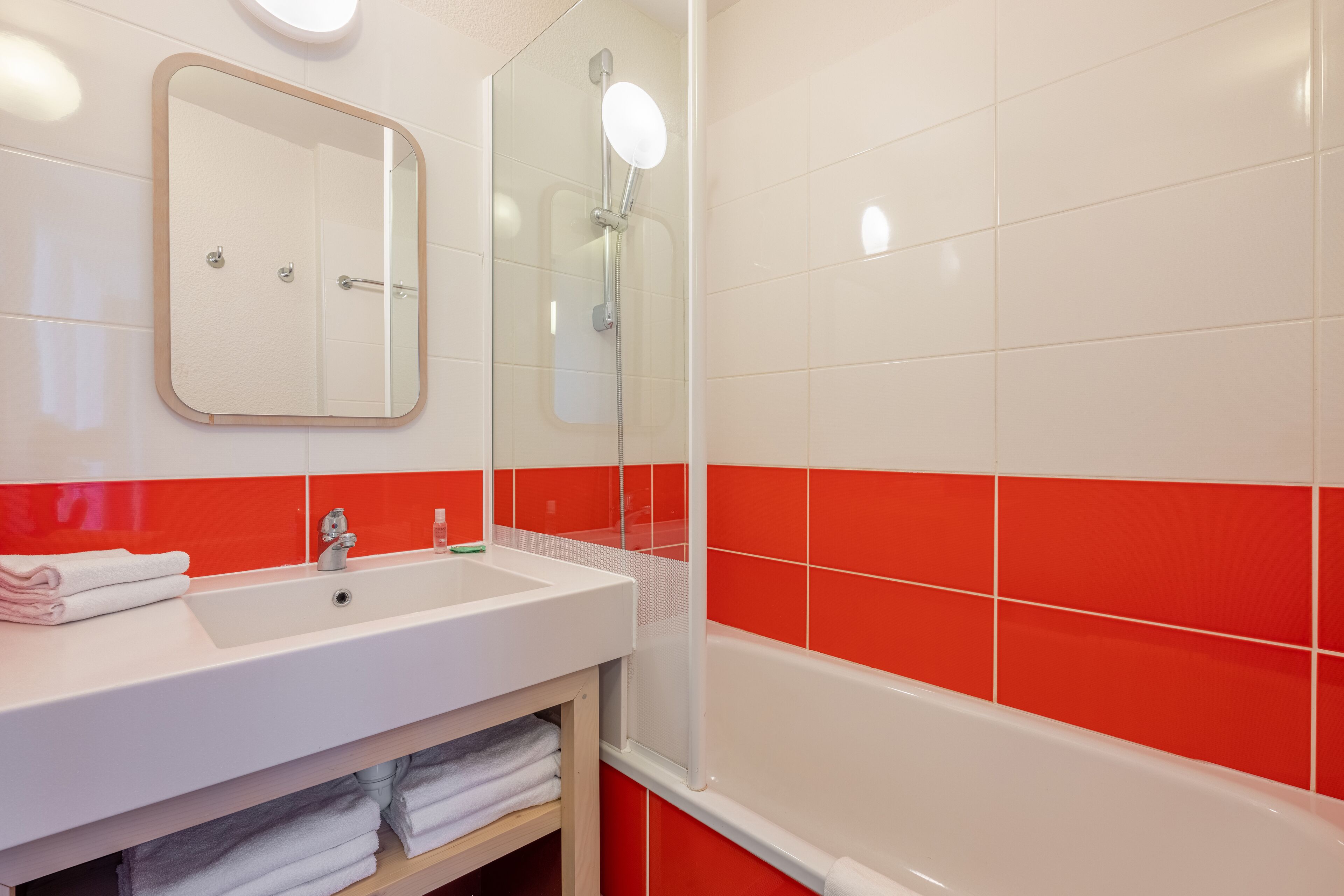 A bathroom with a white sink, a mirror, and a shower.