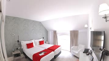 Habitación de hotel con una cama grande, un escritorio con silla, televisión y ventana con cortinas.