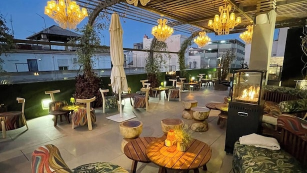 An outdoor patio with cushioned seating, a fire feature, and multiple hanging chandeliers. - Mariposa Hotel Malaga (Málaga)