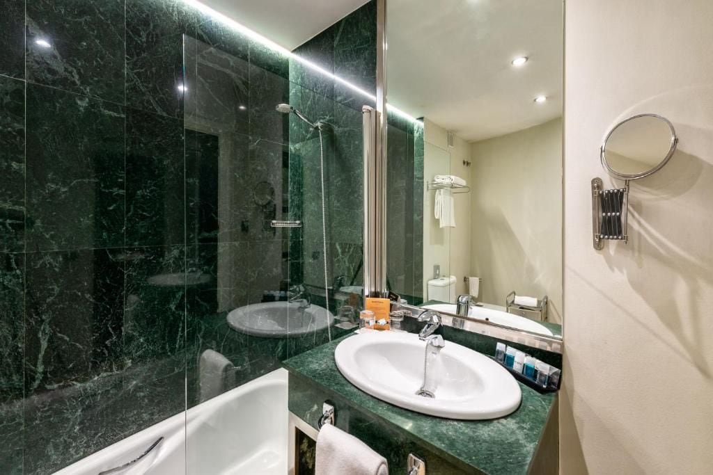 A modern bathroom with a glass-enclosed shower, a white bathtub, and a large mirror.