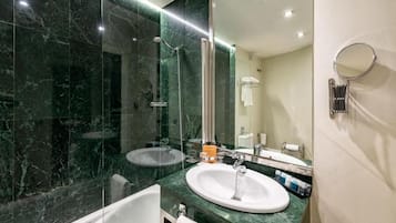 A modern bathroom with a glass-enclosed shower, a white bathtub, and a large mirror.