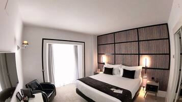 A modern hotel room with a large bed, bedside tables, a desk, and a chair.