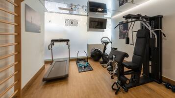 Un gimnasio moderno con caminadora, bicicleta estática y máquinas de pesas.
