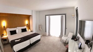 A hotel room with a large bed, a desk with a mirror, and a TV. - Mariposa Hotel Malaga (Málaga)
