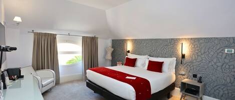 A modern hotel room with a large bed, a desk, and a chair.