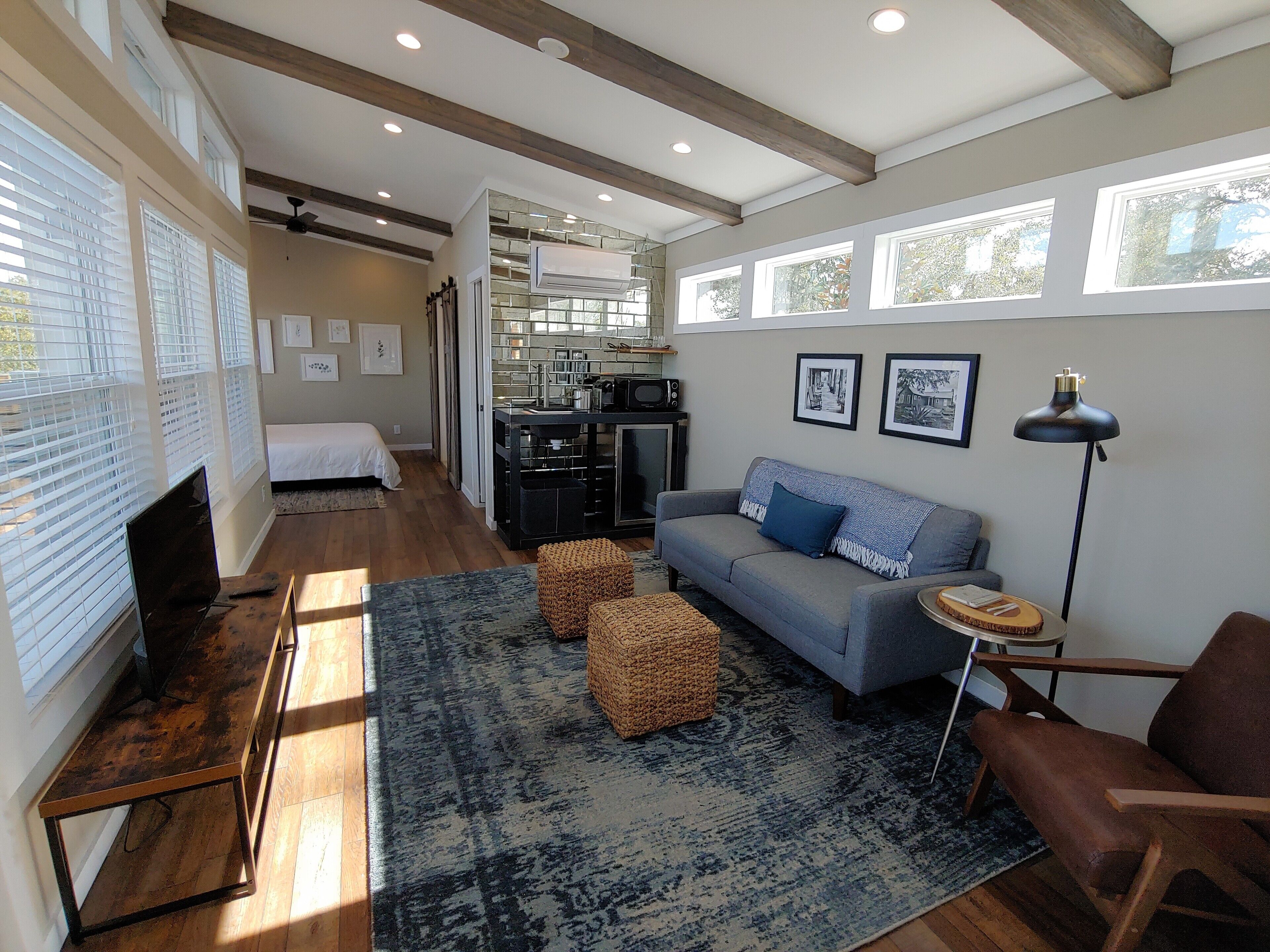A spacious living area with a sofa, a coffee table, and a dining table. There is a kitchen area visible in the background.