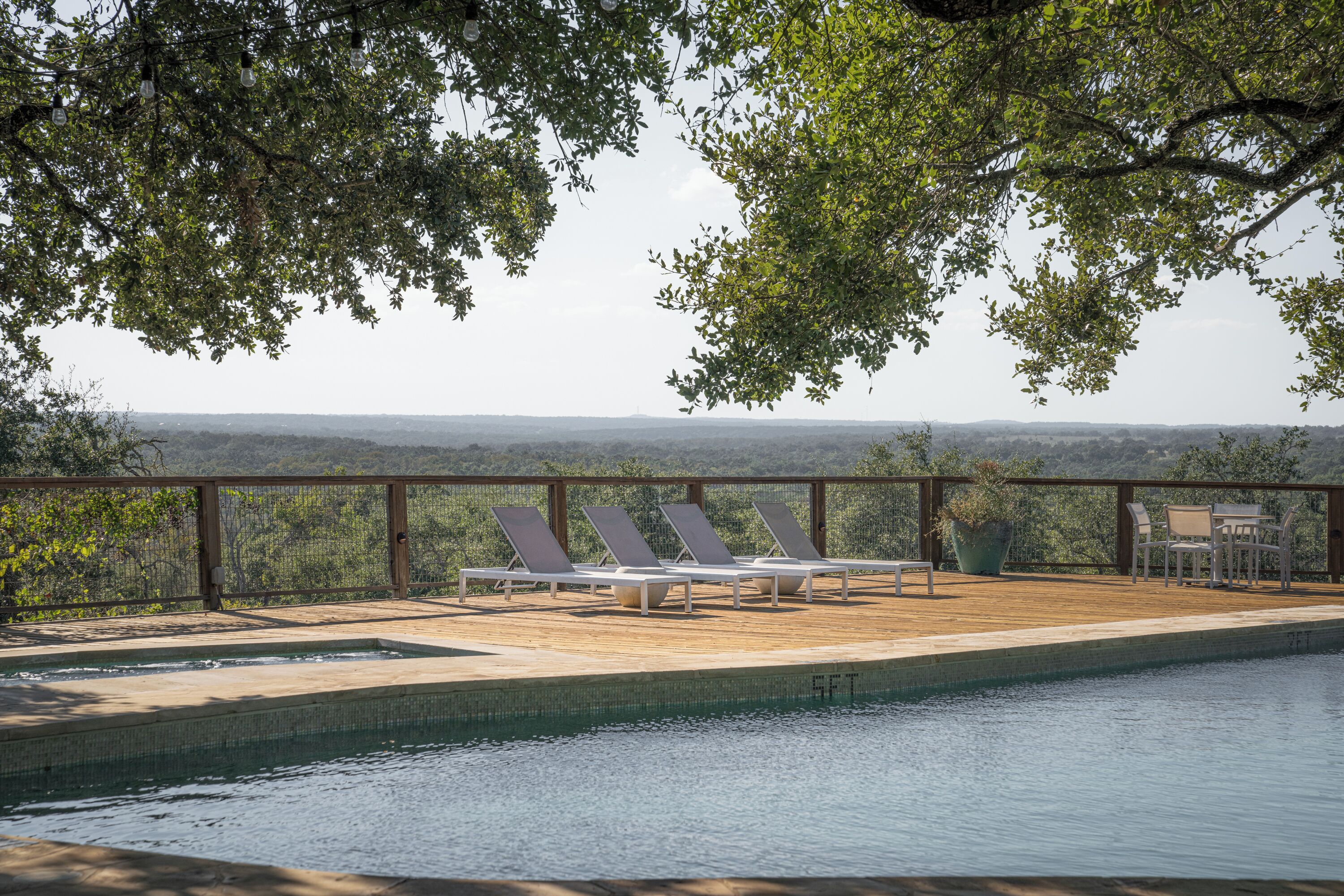 A pool area with lounge chairs and a view of the landscape.