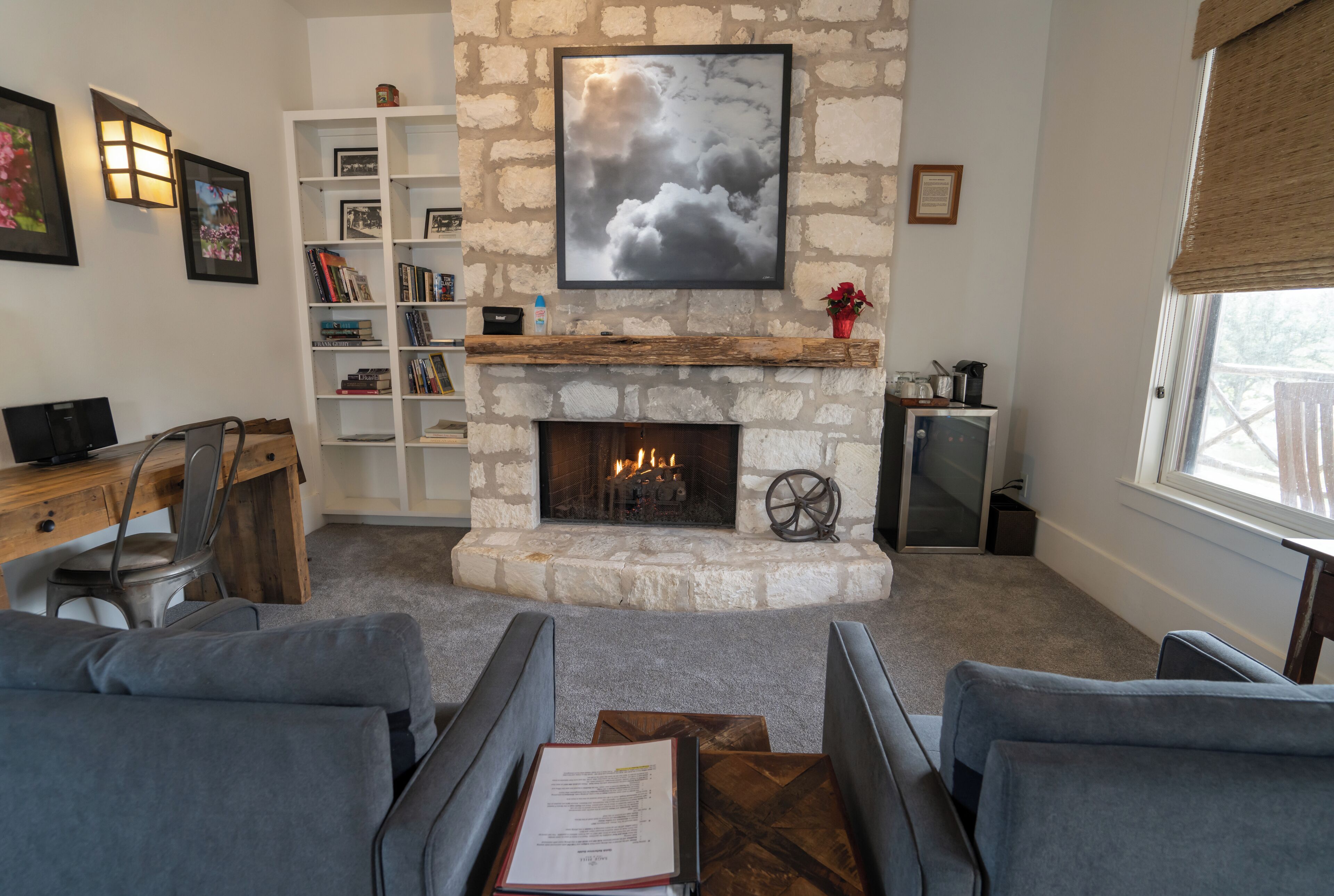 A cozy living room with a stone fireplace, a bookshelf, and a comfortable seating area.