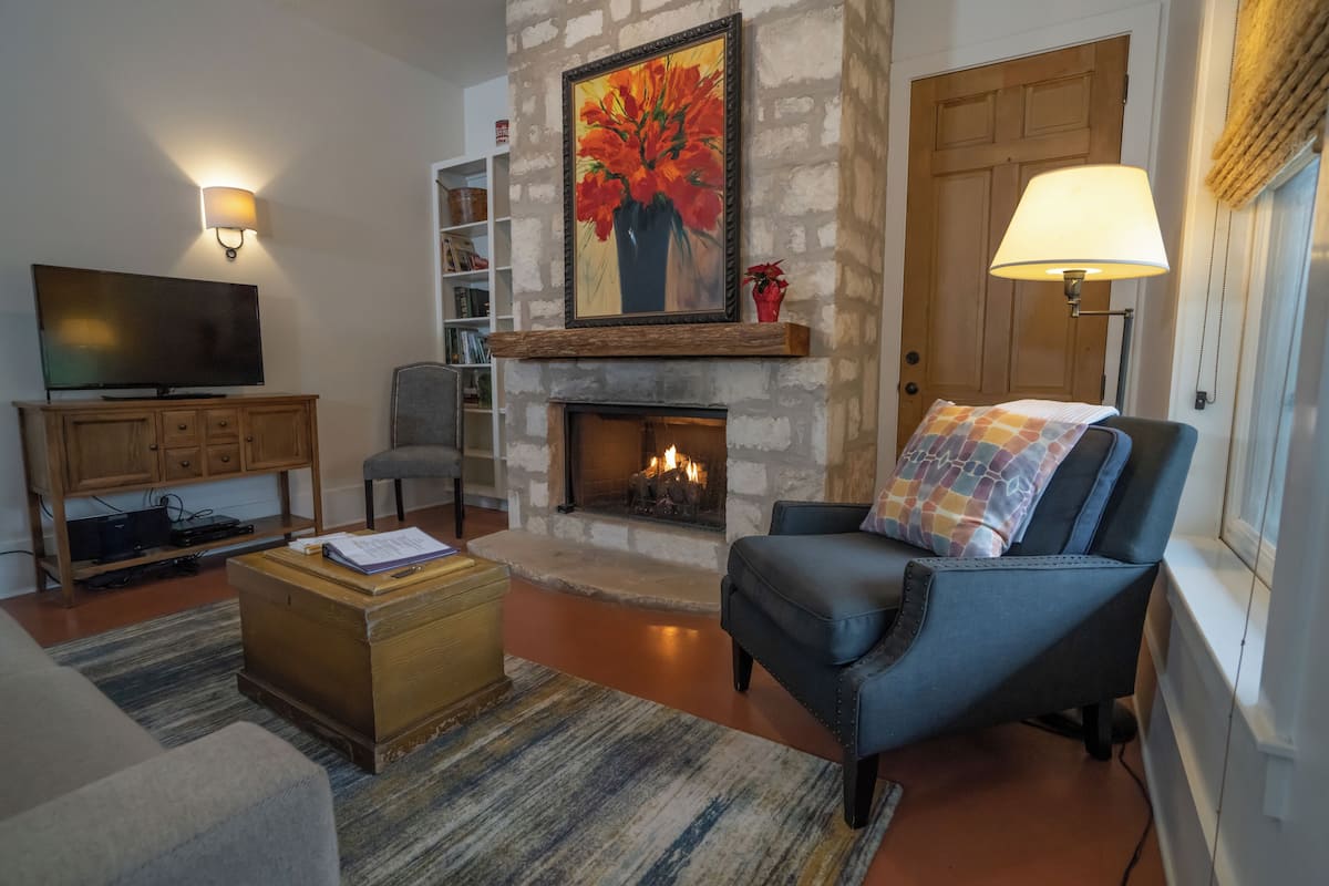 A living room with a stone fireplace, a television, and a comfortable seating area.