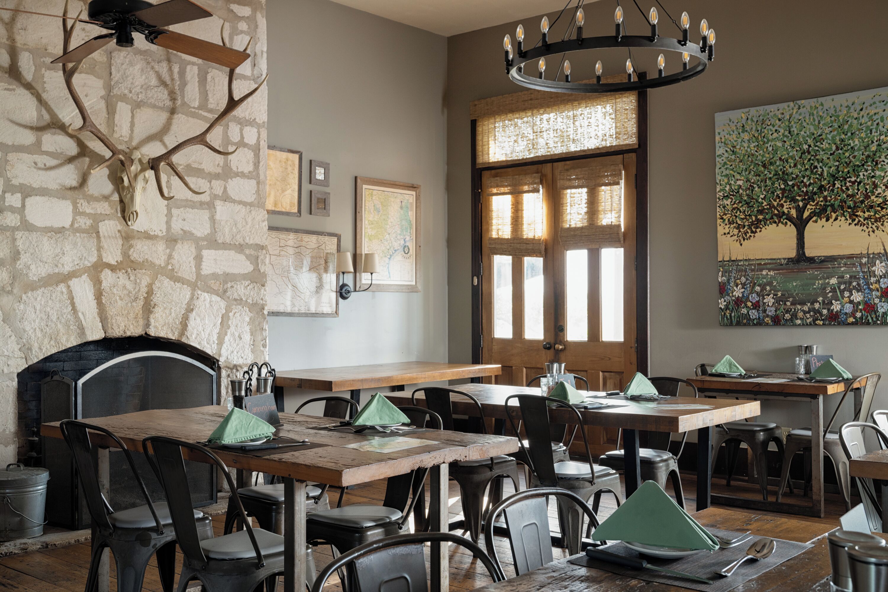 A rustic dining area with stone walls, wooden tables, and metal chairs.