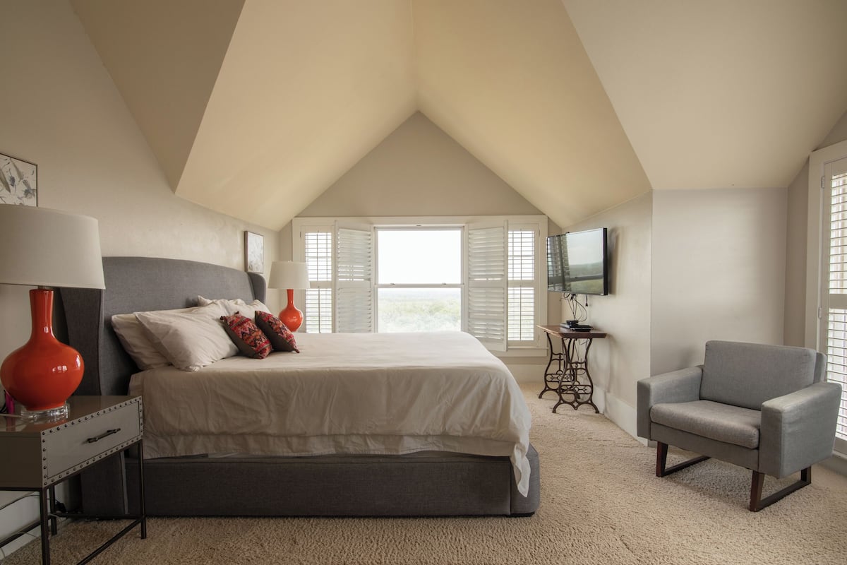 A bedroom with a bed, a chair, a desk, and a TV.