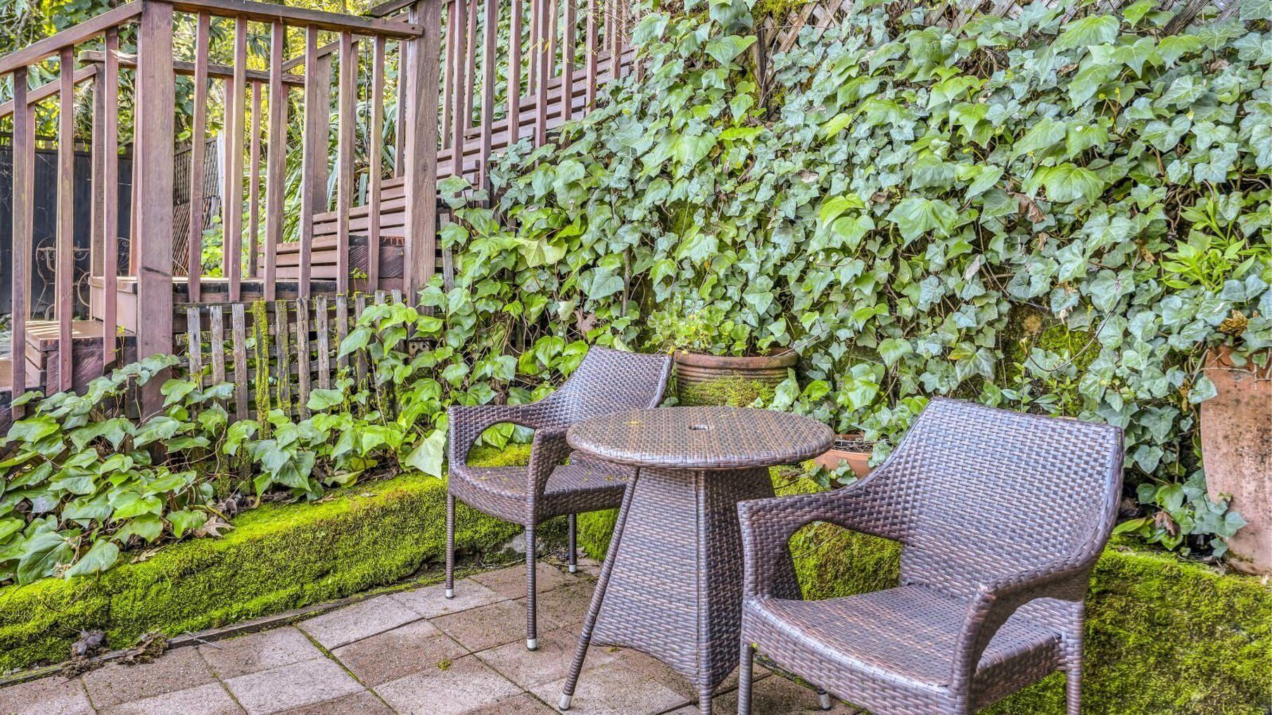 Un'area patio con mobili in vimini e una recinzione in legno.