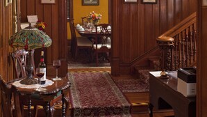 A dining area with wooden paneling, a chandelier, a table set for two, and a staircase leading to another room. - American Guest House (Washington)