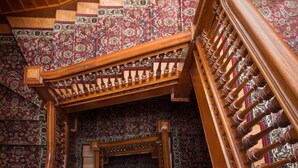 A wooden staircase with intricate carvings and a patterned carpet. - American Guest House (Washington)