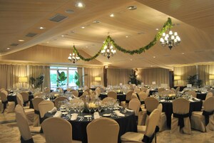 Un salón de banquetes con mesas redondas dispuestas para cenar, candelabros y cortinas decorativas.