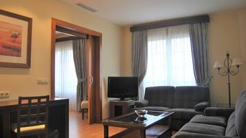 A living room with a sofa, a coffee table, a TV, and a dining area with chairs and a table.