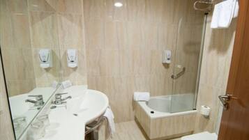 A modern bathroom with a large mirror, a sink, a bathtub, and a toilet.