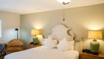 A bedroom with a bed, two nightstands, a chair, a ceiling fan, and two lamps.