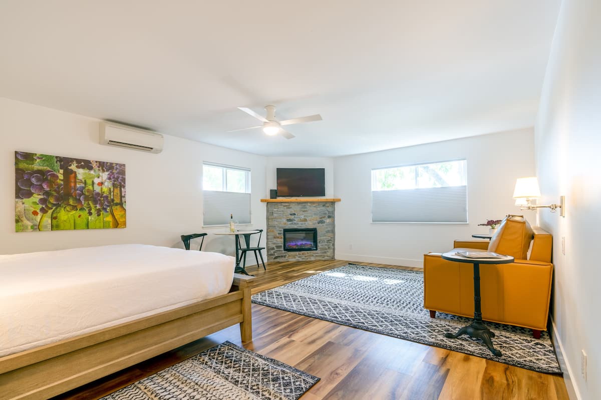 A bedroom with a bed, a fireplace, a sofa, and a small table.
