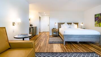 A hotel room with a bed, a chair, a small table, and a nightstand.