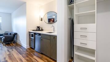 A modern kitchen with a dishwasher, a sink, and a mirror above it. There is a dining area with a table and chairs.