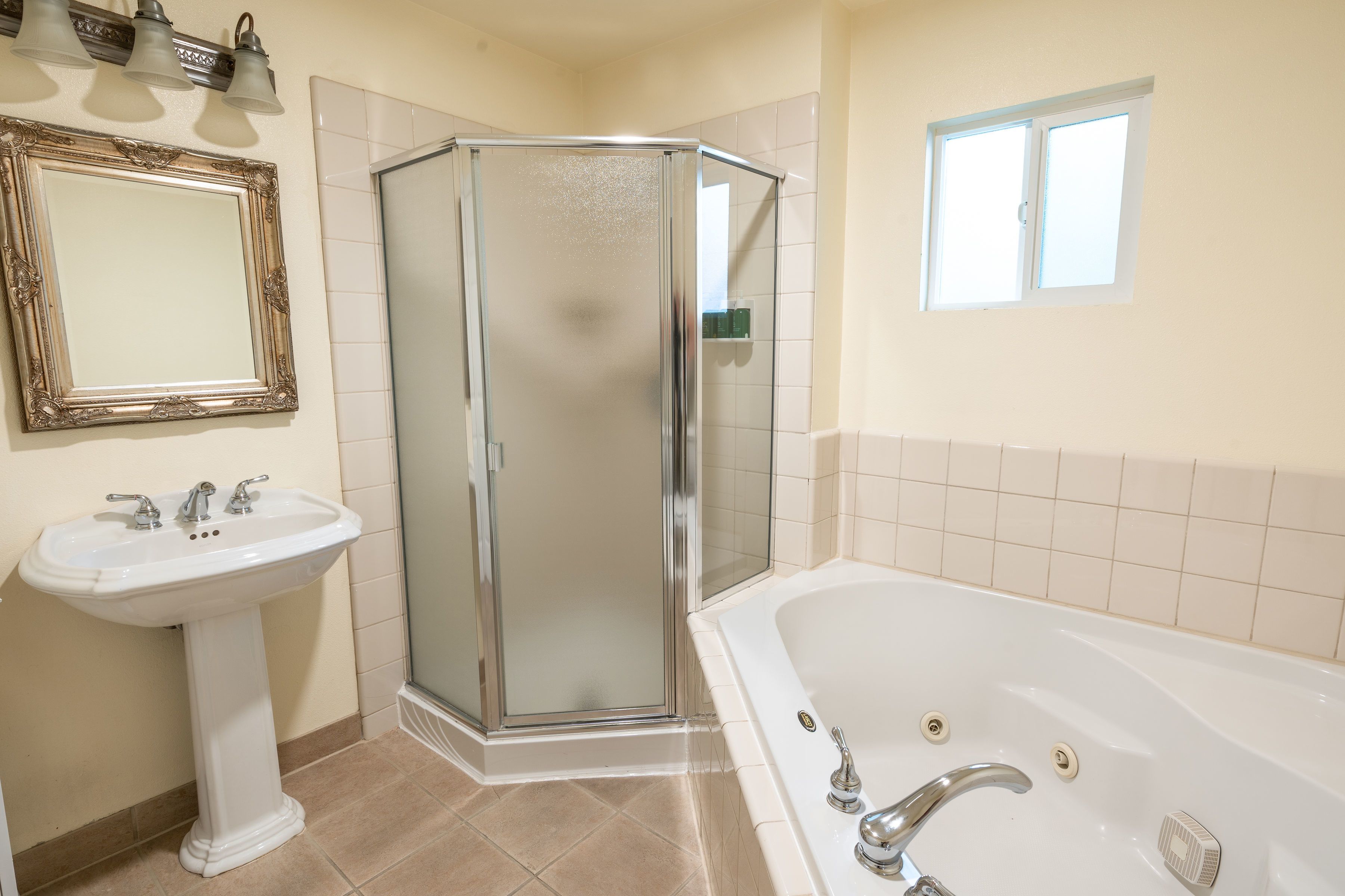 A bathroom with a pedestal sink, a glass shower enclosure, and a bathtub.